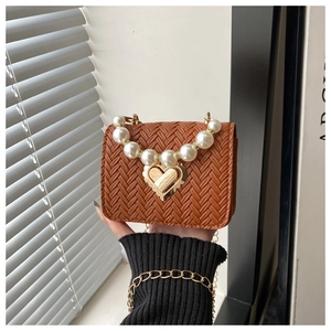 Detailed view of brown woven mini bag with pearl handle and golden heart clasp
