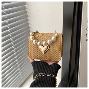 Close-up of khaki woven texture mini bag with pearl handle and golden heart lock