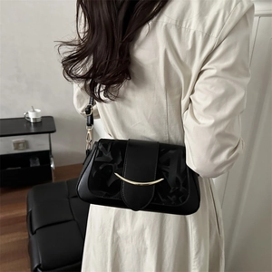 Sac sous le bras minimaliste en cuir noir avec arc doré et détails embossés