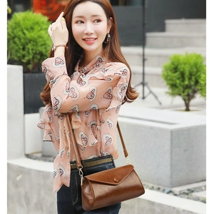 Sac bandoulière vintage en cuir marron foncé avec détails dorés porté par un modèle