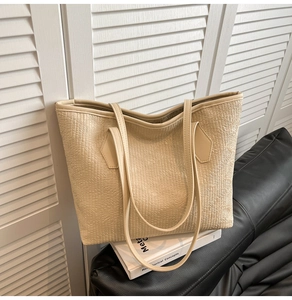 Detail of beige tote bag showing refined geometric embossed texture and sturdy handles