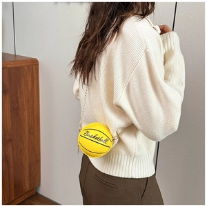 Mini bolso bandolera amarillo con forma de baloncesto y cadena dorada usado por modelo