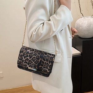 Chic leopard print crossbody bag with gold chain strap worn by a model in minimalist studio