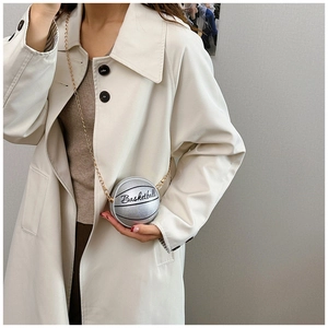 Primer plano de mini bolso plateado con forma de baloncesto y cadena sobre abrigo