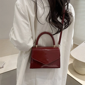 Elegant deep red patent leather handbag for women shown with a stylish white shirt