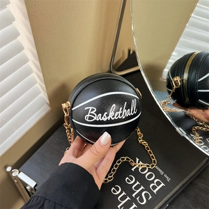 Detailed close-up of a black basketball-shaped crossbody bag with gold chain and zipper