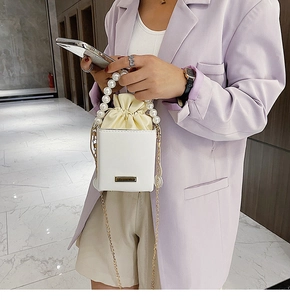 White square handbag with large pearl handle and chain strap shown on a model