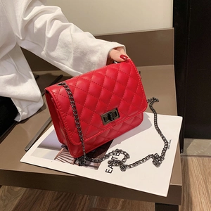 Detail view of red quilted handbag with metal buckle closure and chain strap