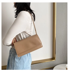 Close-up of the beige crocodile pattern texture and golden metal buckle on the shoulder bag