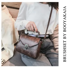Close-up of retro brown PU leather handbag with vintage bronze metal buckle