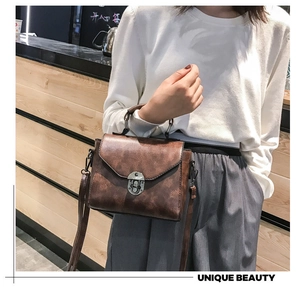 Detail of vintage brown leather handbag featuring a classic retro metal twist lock closure