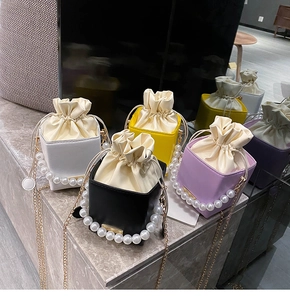 Chic bucket bags with pearl handles and chain straps in four colors on marble