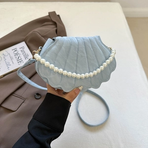 Detail of light blue shell-shaped PU leather bag with quilted texture and pearl handle