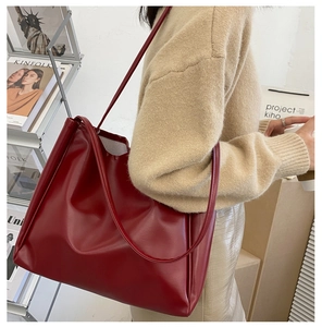 Deep red leather tote bag styled on model's shoulder in a minimalist lifestyle setting