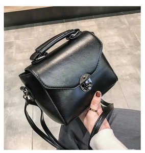 Detailed macro view of the black PU leather texture and metal clasp on small crossbody bag
