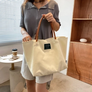 Grande borsa tote in tela crema con manici in pelle marrone ed etichetta vintage in interni