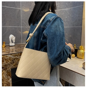 Dettaglio borsa trapuntata beige con tracolla annodata e cuciture a rombi eleganti