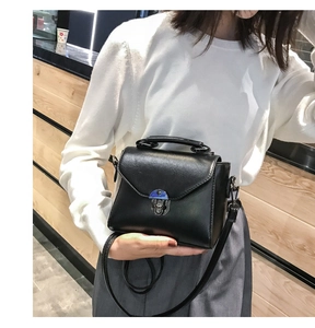 Detailed view of a black leather handbag featuring a metal buckle and detachable shoulder strap