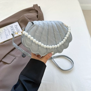 Close-up of shell-shaped handbag featuring premium pearl handle and curved embossed texture