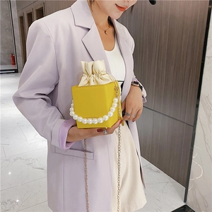 Yellow box bag with large pearl handle and gold chain strap styled on purple blazer