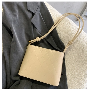 Dettaglio borsa trapuntata beige con tracolla a nodi su tessuto strutturato