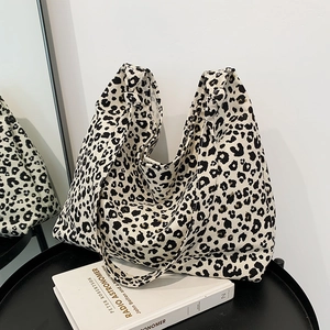 Grande borsa tote in tela leopardata con manici a nodo su un tavolo nero lucido