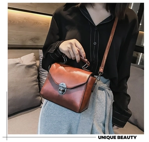 Close-up of vintage brown leather handbag with metal lock and adjustable strap