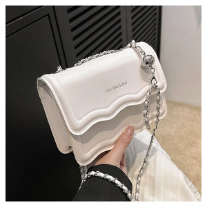 Detail of white leather crossbody bag with wave edge cover and silver ball chain