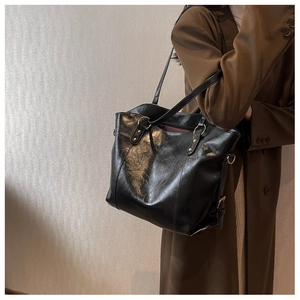Détail du sac cabas en cuir noir avec texture brillante et détails en métal doré chic