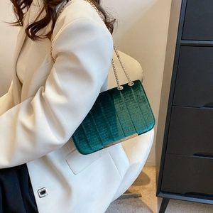 Sac bandoulière chic en velours vert foncé avec plis, porté par un mannequin en costume