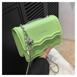 Detail of green chain shoulder bag with unique wavy edge design and silver ball clasp