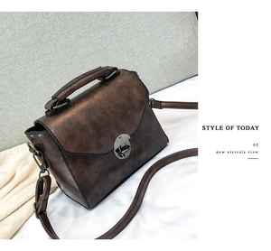 Detail view of a vintage brown leather handbag featuring a metal twist lock and top handle