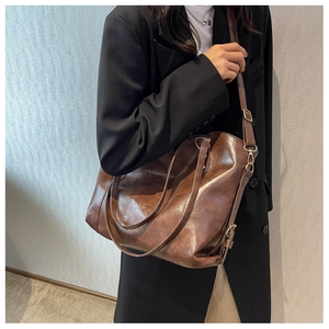 Sac fourre-tout marron en cuir huilé porté par un modèle au style rétro chic