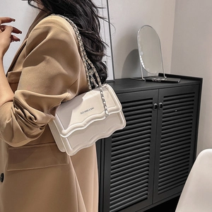 Chic cream leather crossbody bag with silver chain strap and unique wavy edge design