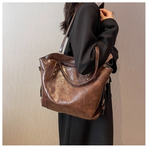 Sac fourre-tout marron rétro avec rivets métalliques et cuir texturé porté par un modèle