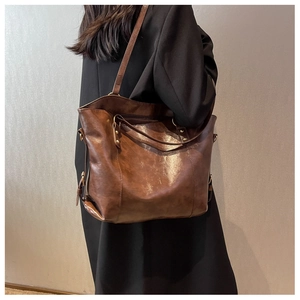 Détail du sac cabas en cuir marron brillant avec boucle métallique et bandoulière élégante