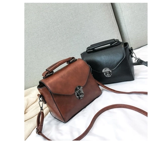 Close-up of black and brown vintage crossbody bags with metal buckles and top handles