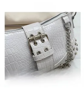Detail der weißen Tasche mit Krokodil-Prägung, Metallschnalle und eleganter Silberkette