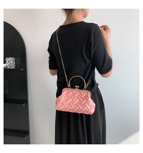Detail of pink woven shell bag featuring golden chain and metal handle over black dress