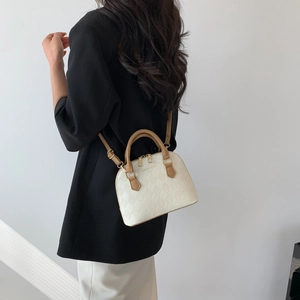 Sac à main matelassé en similicuir beige avec poignées marron porté par un mannequin