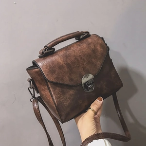 Detail of vintage brown faux leather handbag with classic metal buckle and textured finish