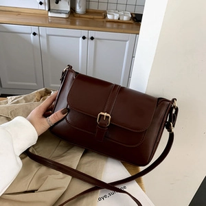 Detailed view of dark brown vintage faux leather crossbody bag with antique gold buckle
