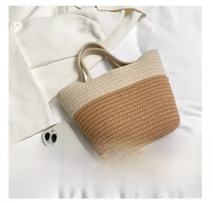 Size comparison of a two-tone woven bucket bag next to a smartphone on soft fabric