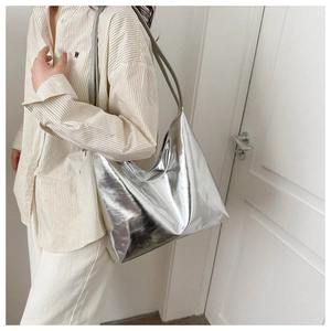 Close-up of a silver metallic tote bag with reflective texture on a model shoulder