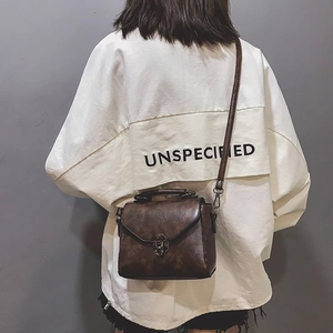 Detail of vintage dark brown crossbody bag with metal lock shown on model's shoulder