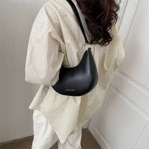 Minimalist black crescent hobo underarm bag with gold lettering shown on model