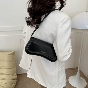 Chic black leather underarm shoulder bag with gold logo on a white blazer outfit