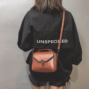 Brown vintage PU leather shoulder bag with metallic buckle shown in a lifestyle street setting