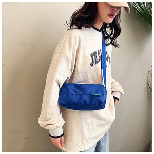 Dettaglio di una borsa a tracolla cilindrica blu navy in nylon con tracolla regolabile