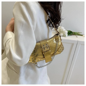 Goldene Umhängetasche in Krokodilleder-Optik mit Nieten und Silberkette am Modell